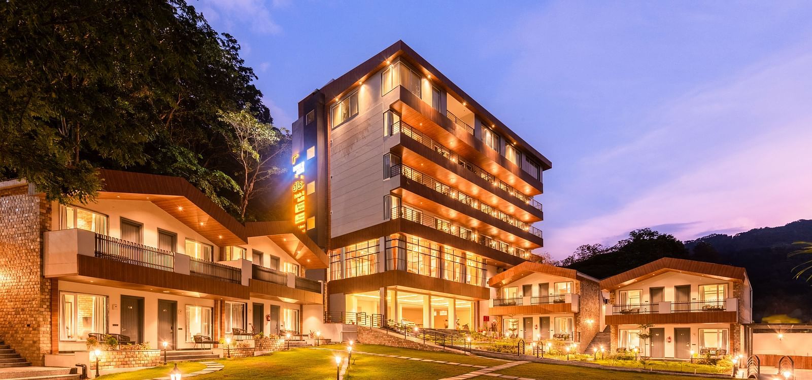 Exterior facade view of DLS Divine River Resort and Spa with warm lighting and garden area taken in the evening 